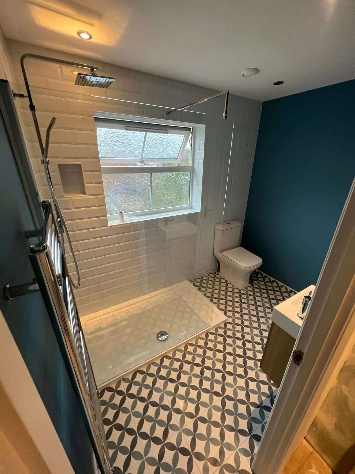 Bathroom installation by Space B Tiling: teal-accented bathroom with shower and patterned floor