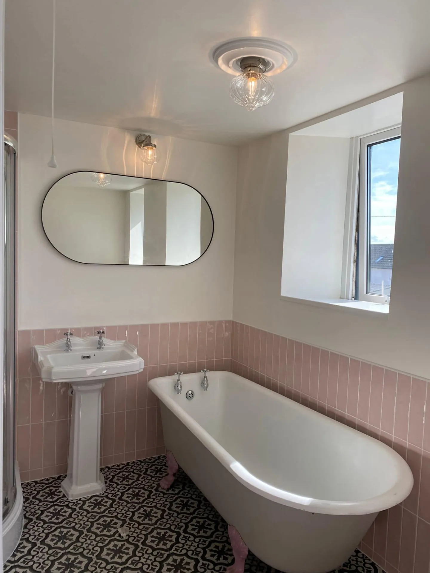Bathroom installation by Space B Tiling: roll-top bath with pink tiling and patterned floor tiles