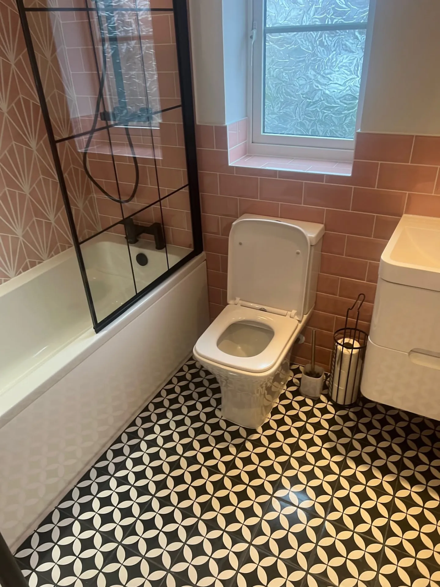Bathroom installation by Space B Tiling: pink metro tiles and black and white patterned floor
