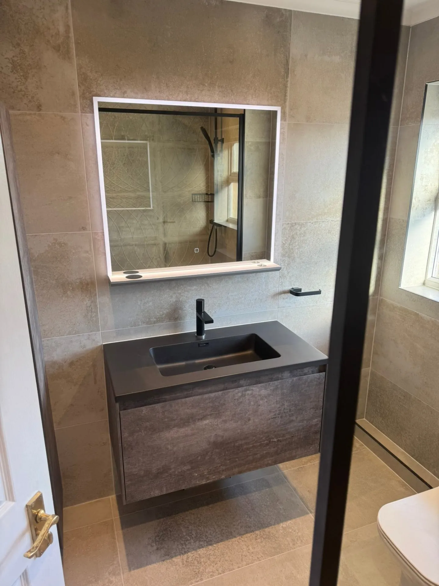 Bathroom installation by Space B Tiling: dark vanity basin with taupe stone-effect tiles