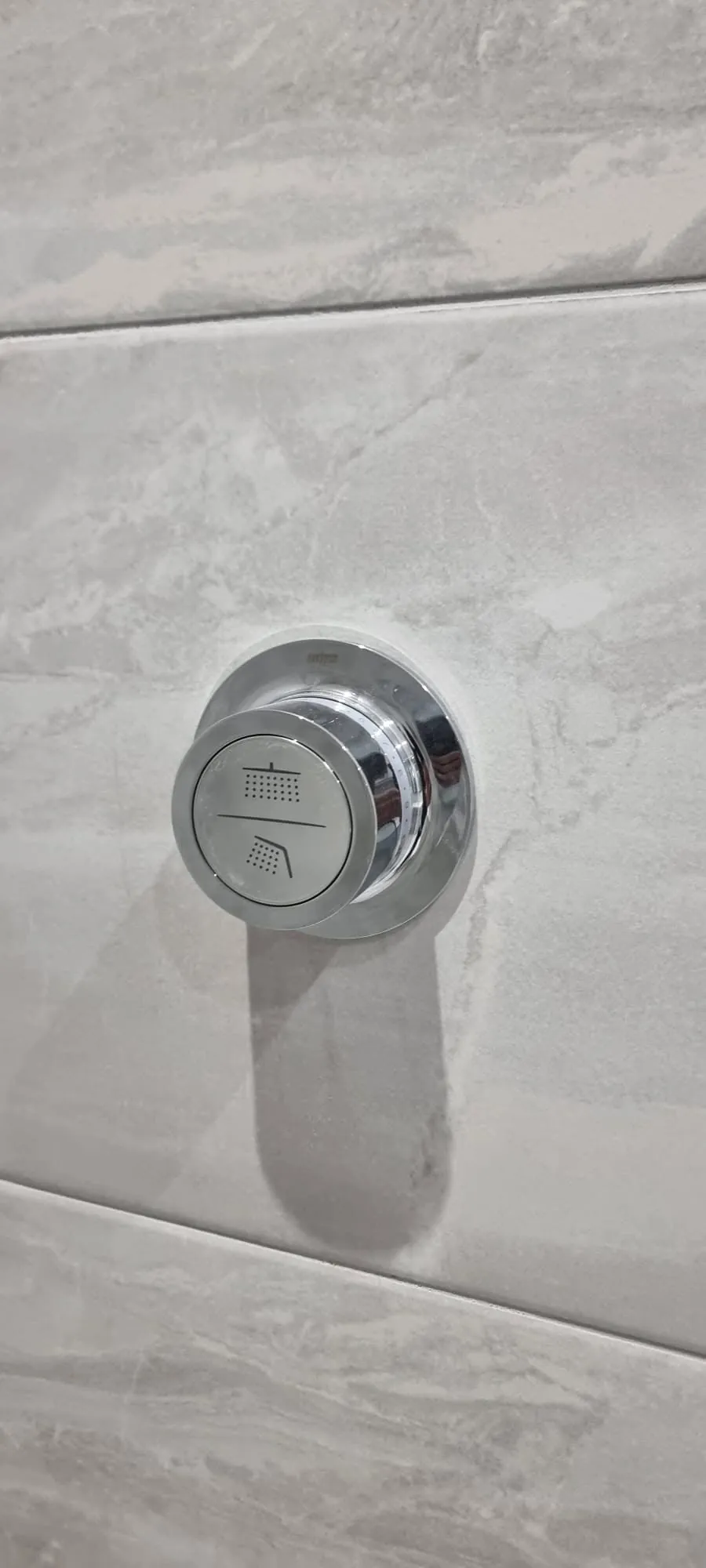 Bathroom installation by Space B Tiling: chrome shower control on marble-effect tiles
