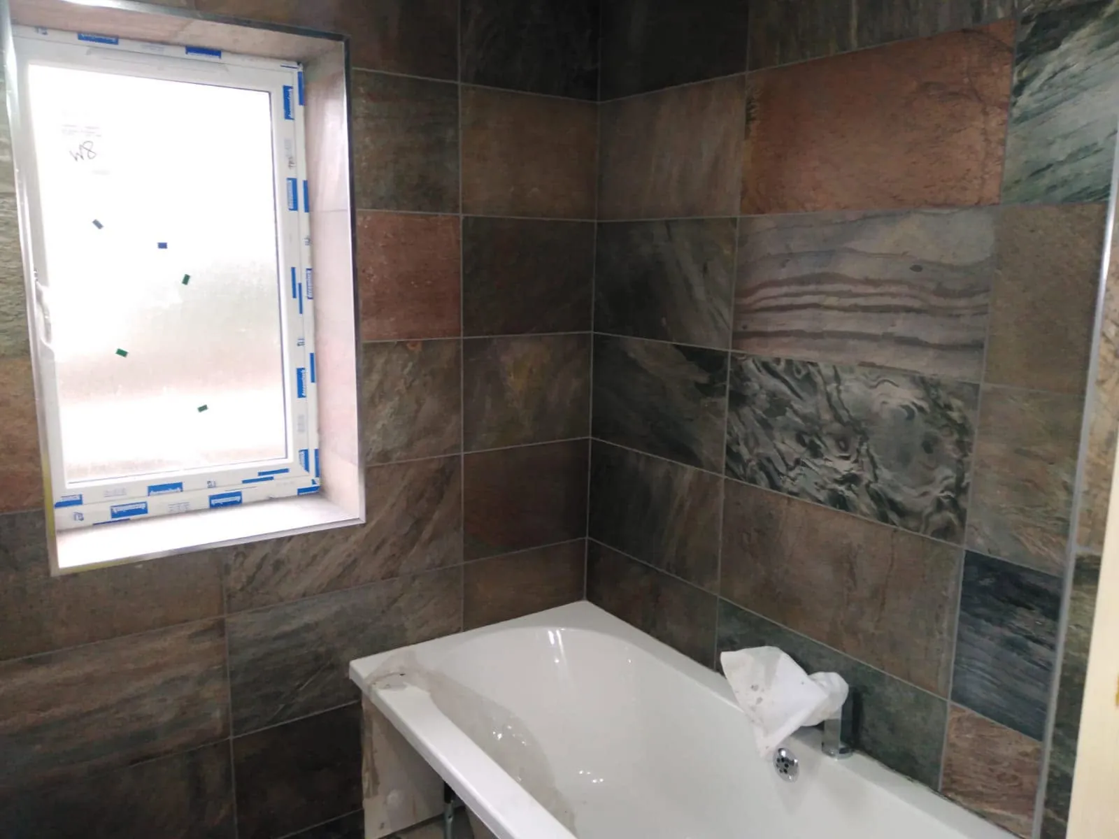 Wall tiling by Space B Tiling: slate-effect wall tiles around bath and window