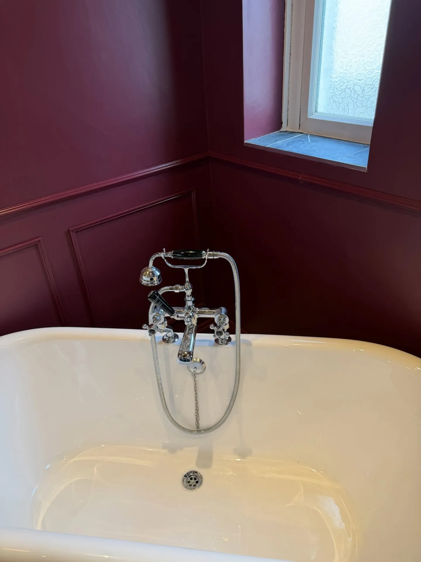 Bathroom installation by Space B Tiling: traditional bath mixer against burgundy panelled walls