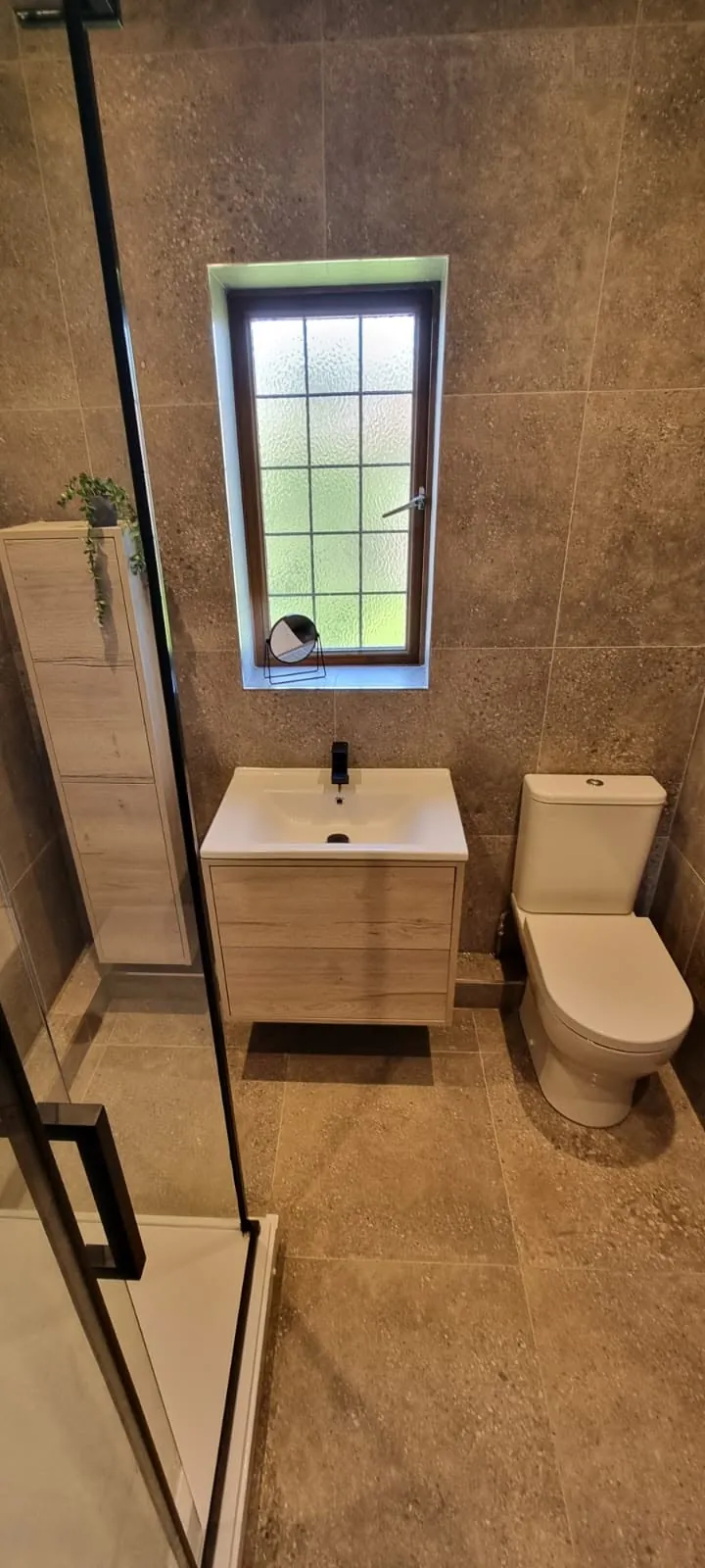 Bathroom installation by Space B Tiling: shower enclosure with vanity and toilet in taupe tiles