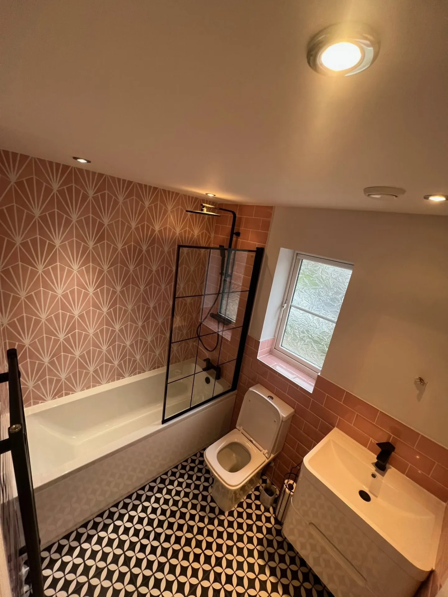 Bathroom installation by Space B Tiling: pink geometric feature wall with shower over bath