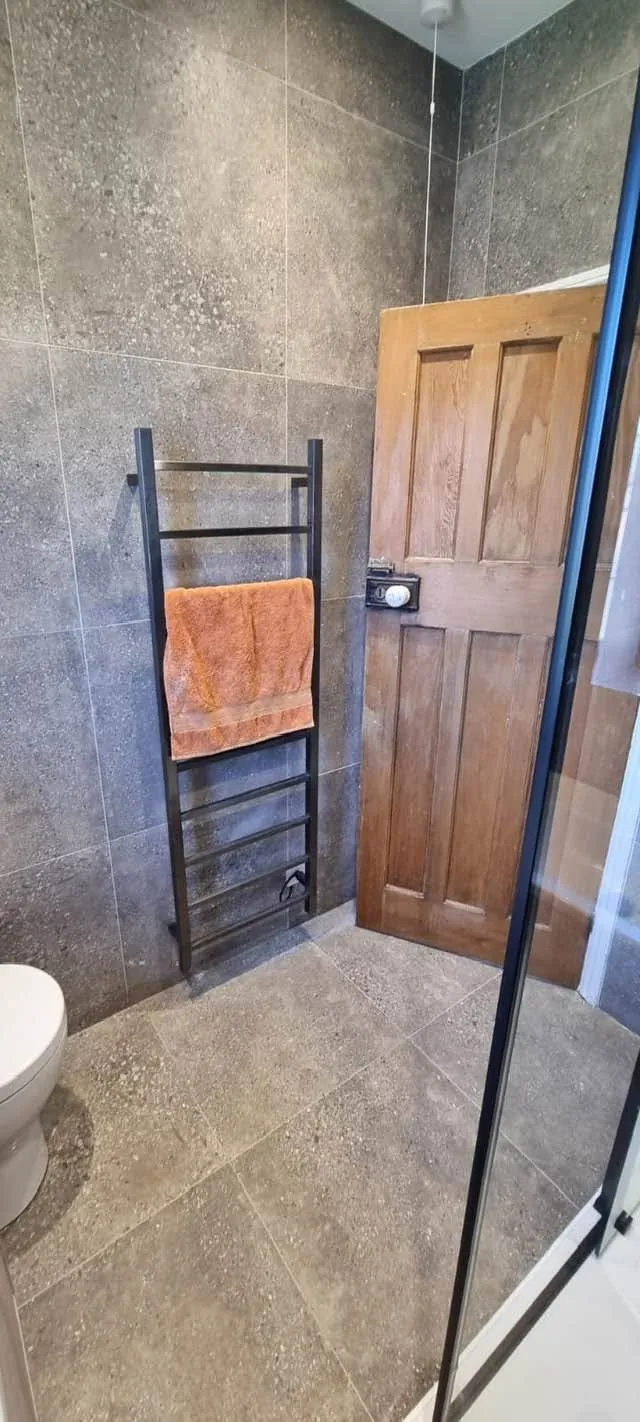 Bathroom installation by Space B Tiling: towel radiator against stone-effect wall tiles