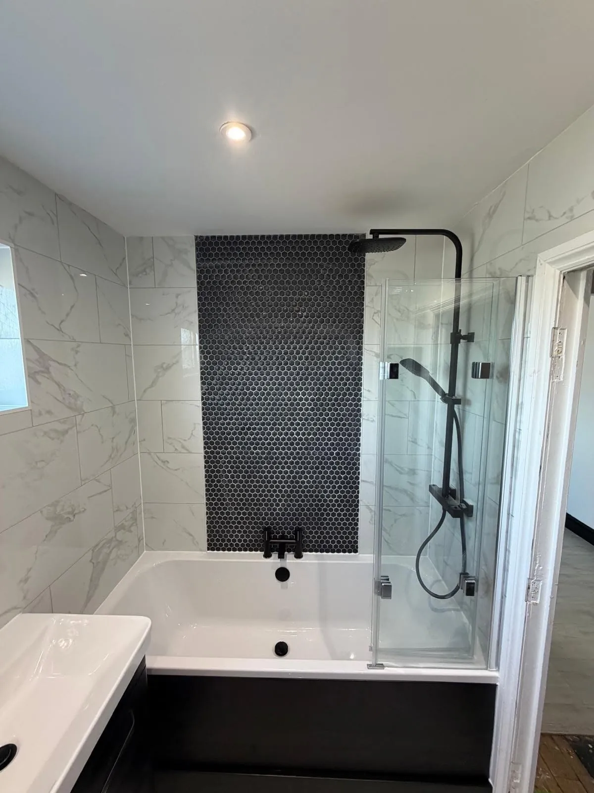 Bathroom installation by Space B Tiling: black hexagon mosaic feature wall behind bath