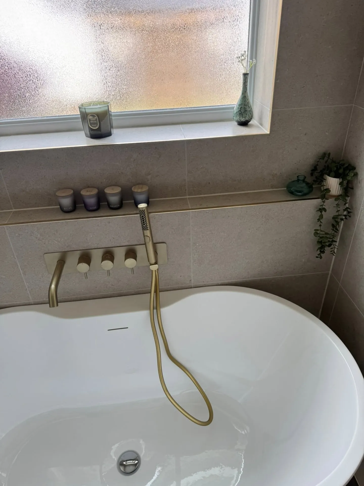 Bathroom installation by Space B Tiling: brushed brass wall-mounted bath filler and tiled shelf