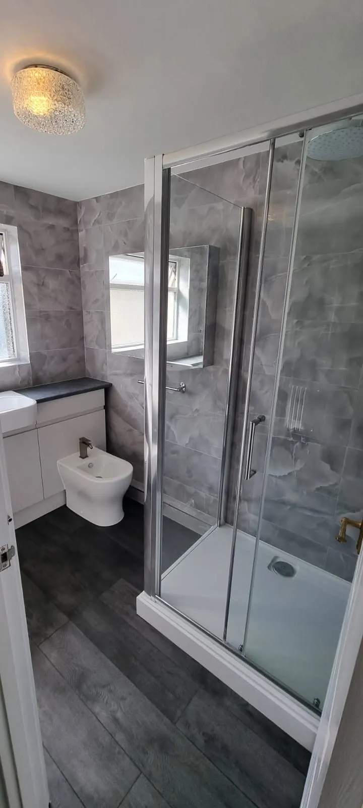 Bathroom installation by Space B Tiling: shower enclosure and bidet in a grey-tiled bathroom