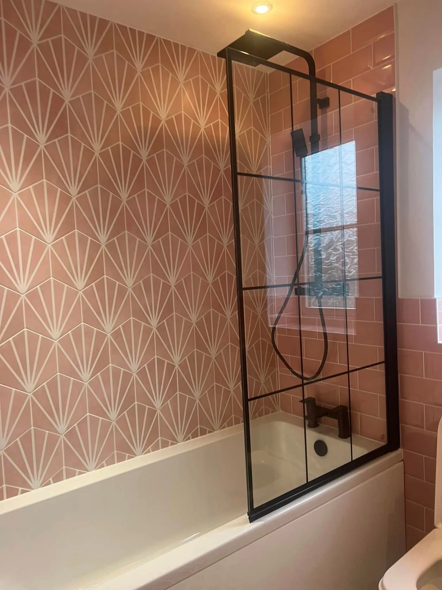 Bathroom installation by Space B Tiling: bath with black-framed screen and pink feature tiles