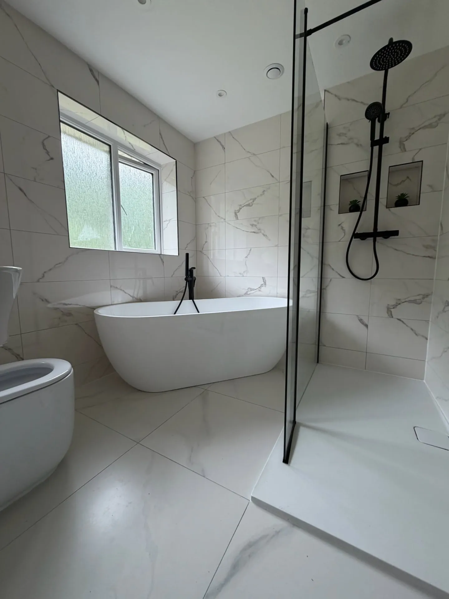 Bathroom installation by Space B Tiling: freestanding bath and walk-in shower with marble-effect tiles