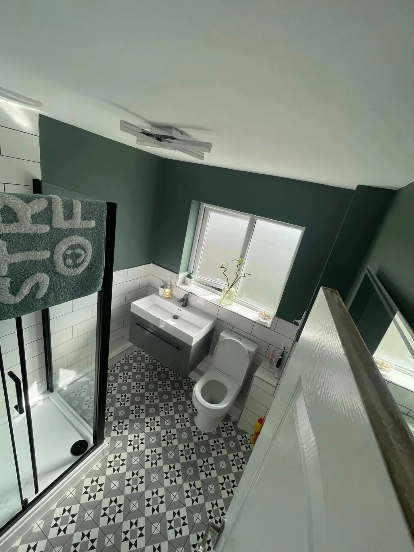Bathroom installation by Space B Tiling: dark green walls with patterned floor tiles and wall-hung basin
