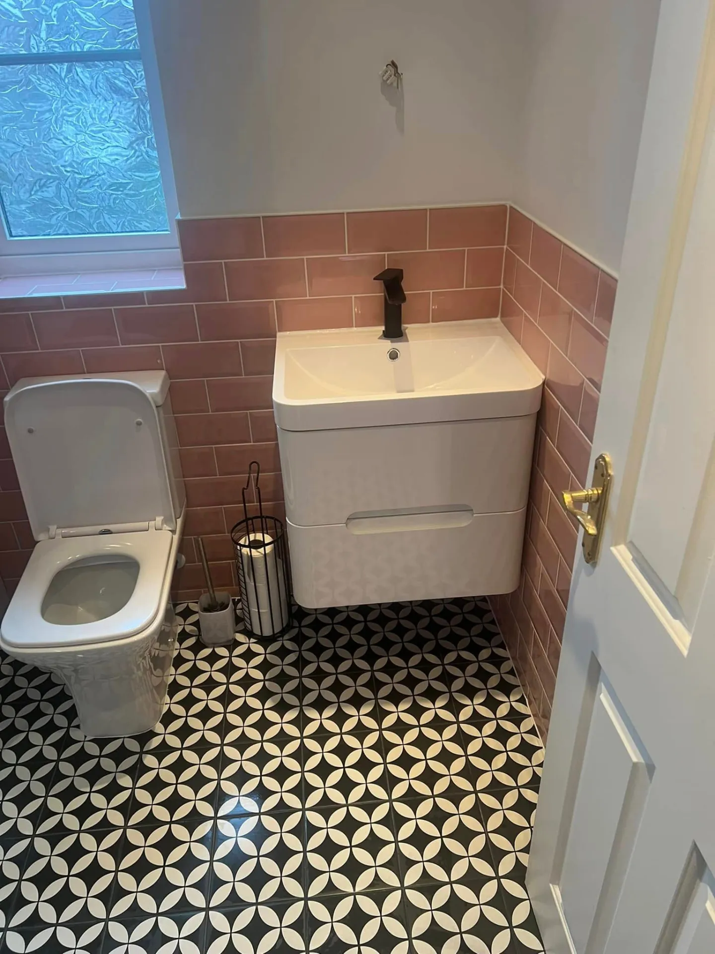 Bathroom installation by Space B Tiling: toilet and basin against pink tiles with geometric floor