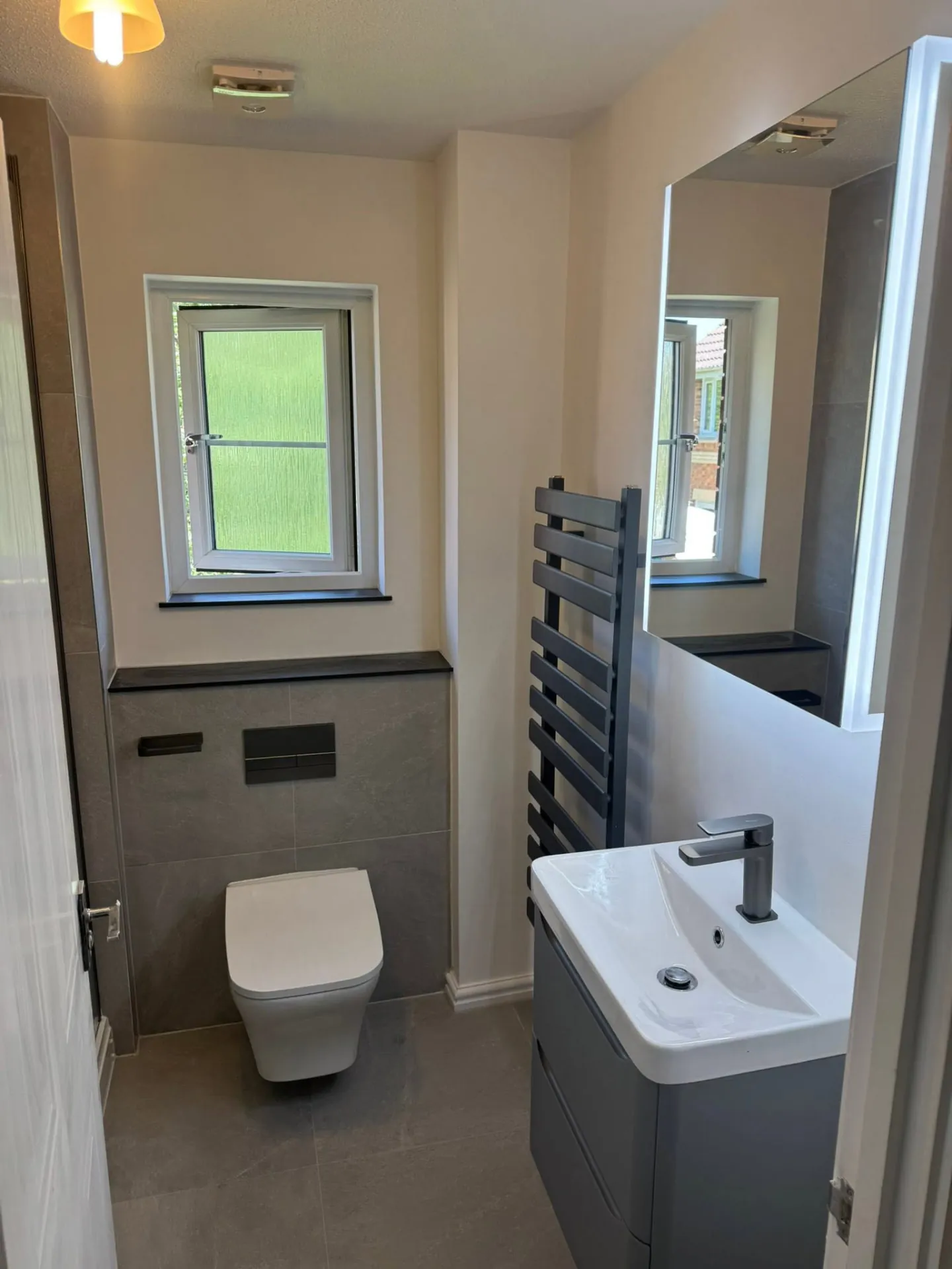 Bathroom installation by Space B Tiling: modern vanity and toilet with dark grey fittings