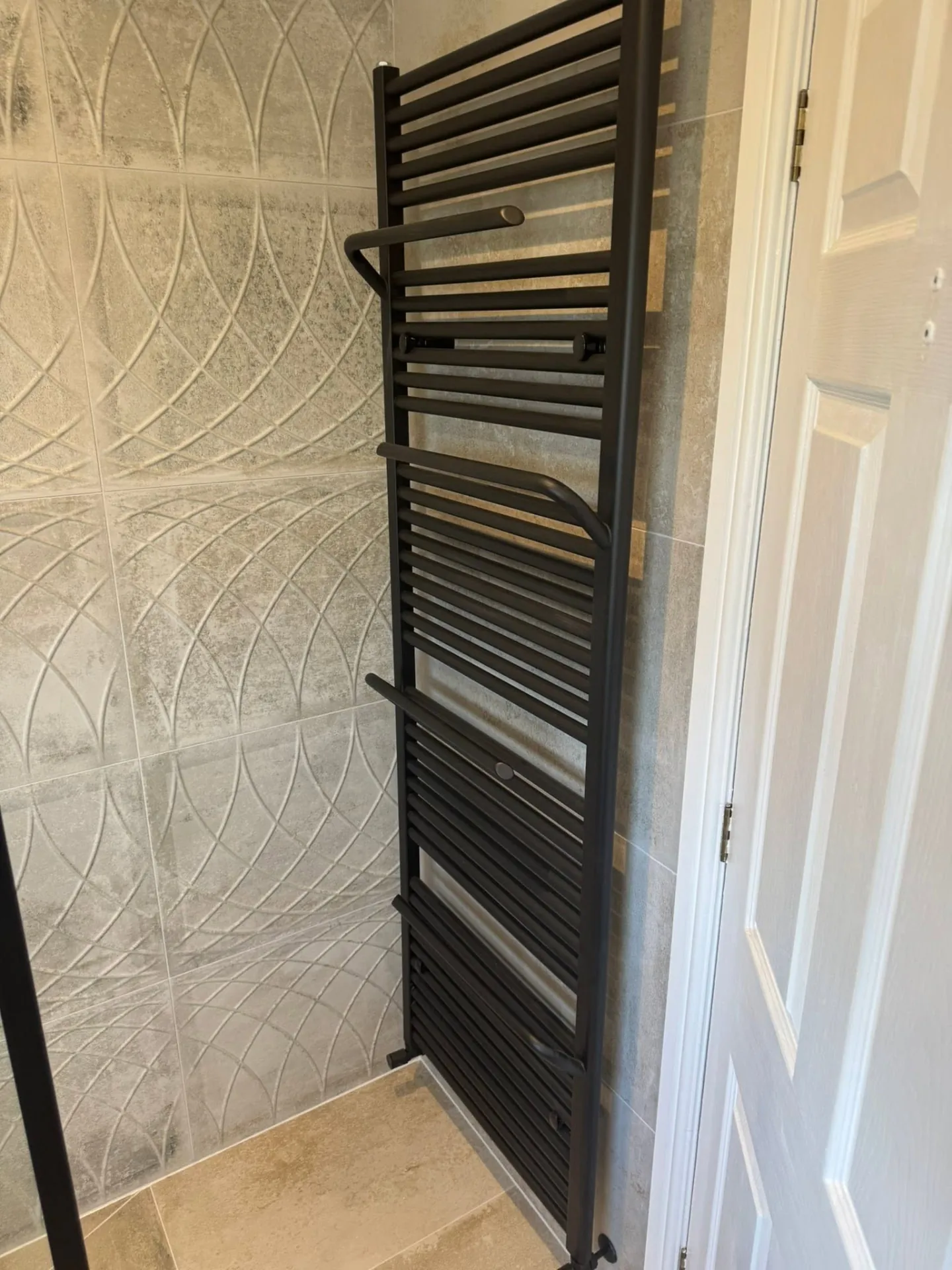Bathroom installation by Space B Tiling: dark towel radiator and decorative wall tiles