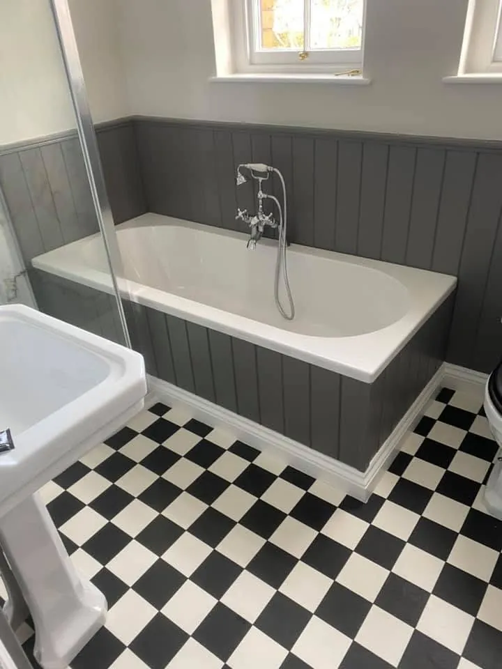 Bathroom installation by Space B Tiling: bath with grey panelling and black and white chequered floor tiles
