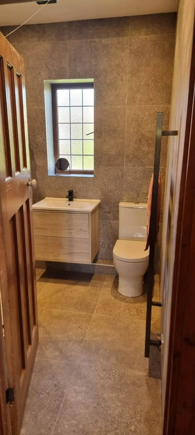 Bathroom installation by Space B Tiling: vanity, toilet and stone-effect tiling in a narrow bathroom