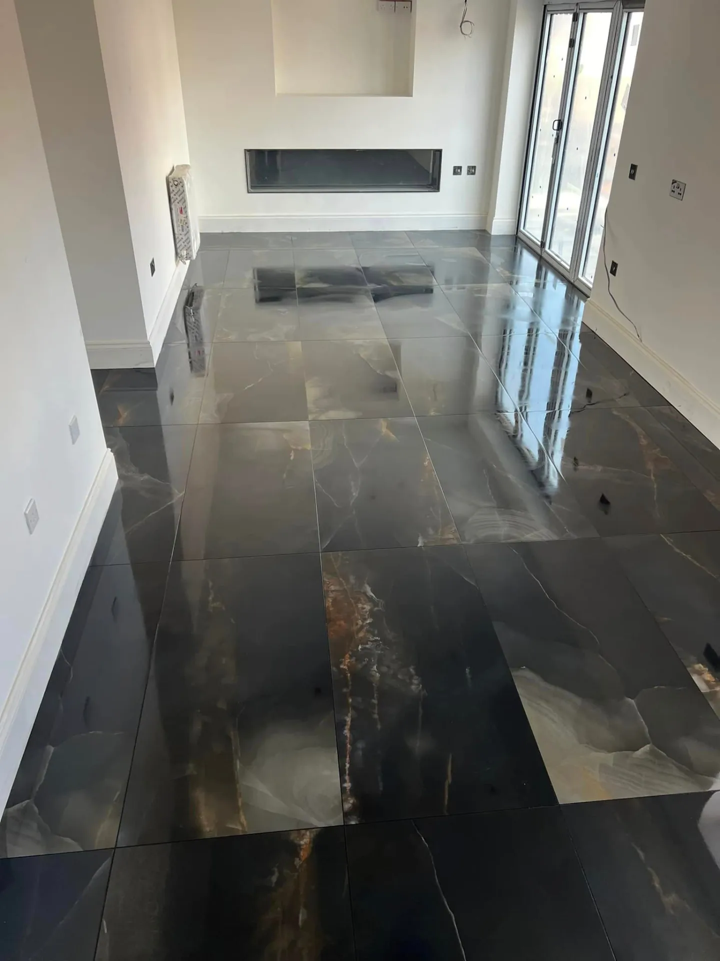 Floor tiling by Space B Tiling: large-format polished dark floor tiles in an open-plan room