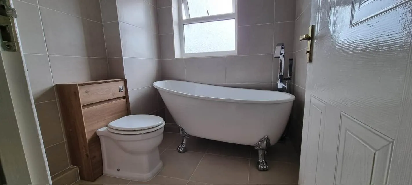 Bathroom installation by Space B Tiling: freestanding bath in a taupe-tiled bathroom