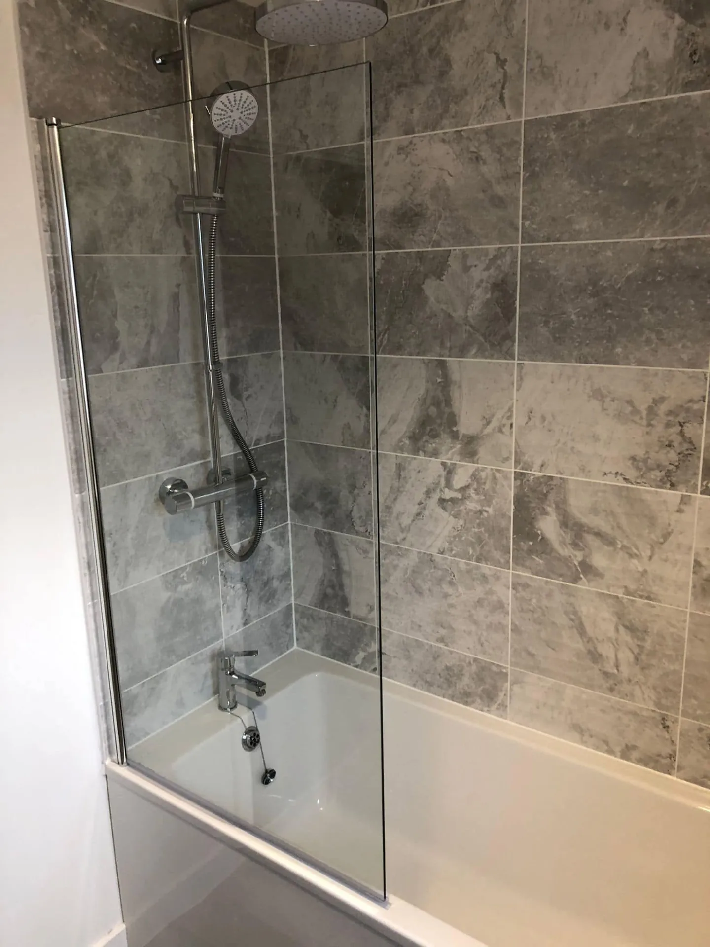 Bathroom installation by Space B Tiling: shower over bath with large grey stone-effect tiles