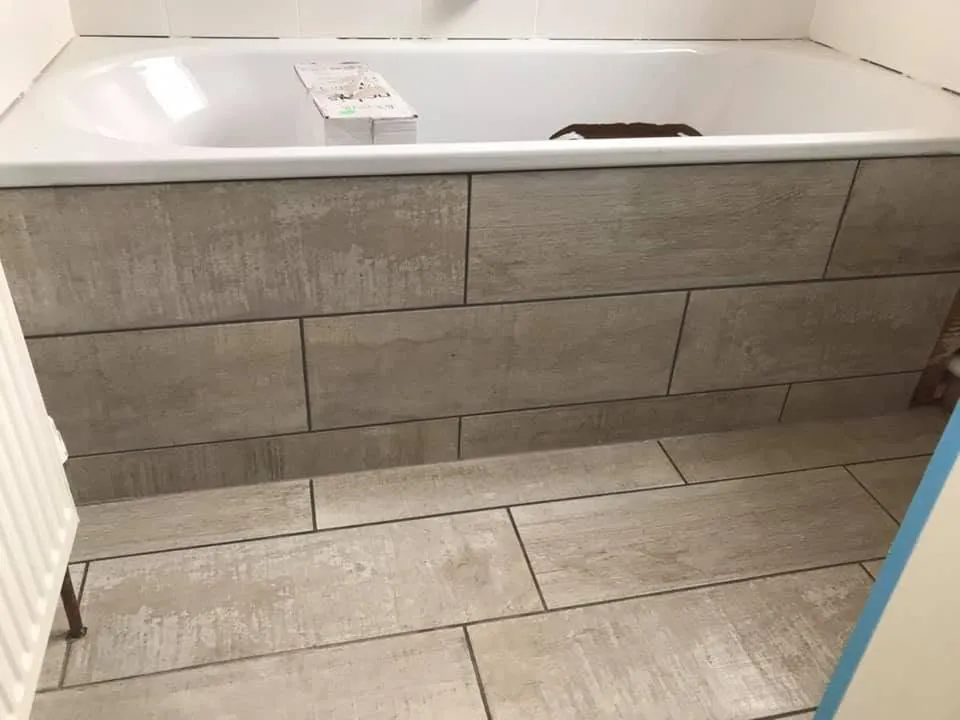 Floor tiling by Space B Tiling: wood-effect floor tiles and tiled bath panel