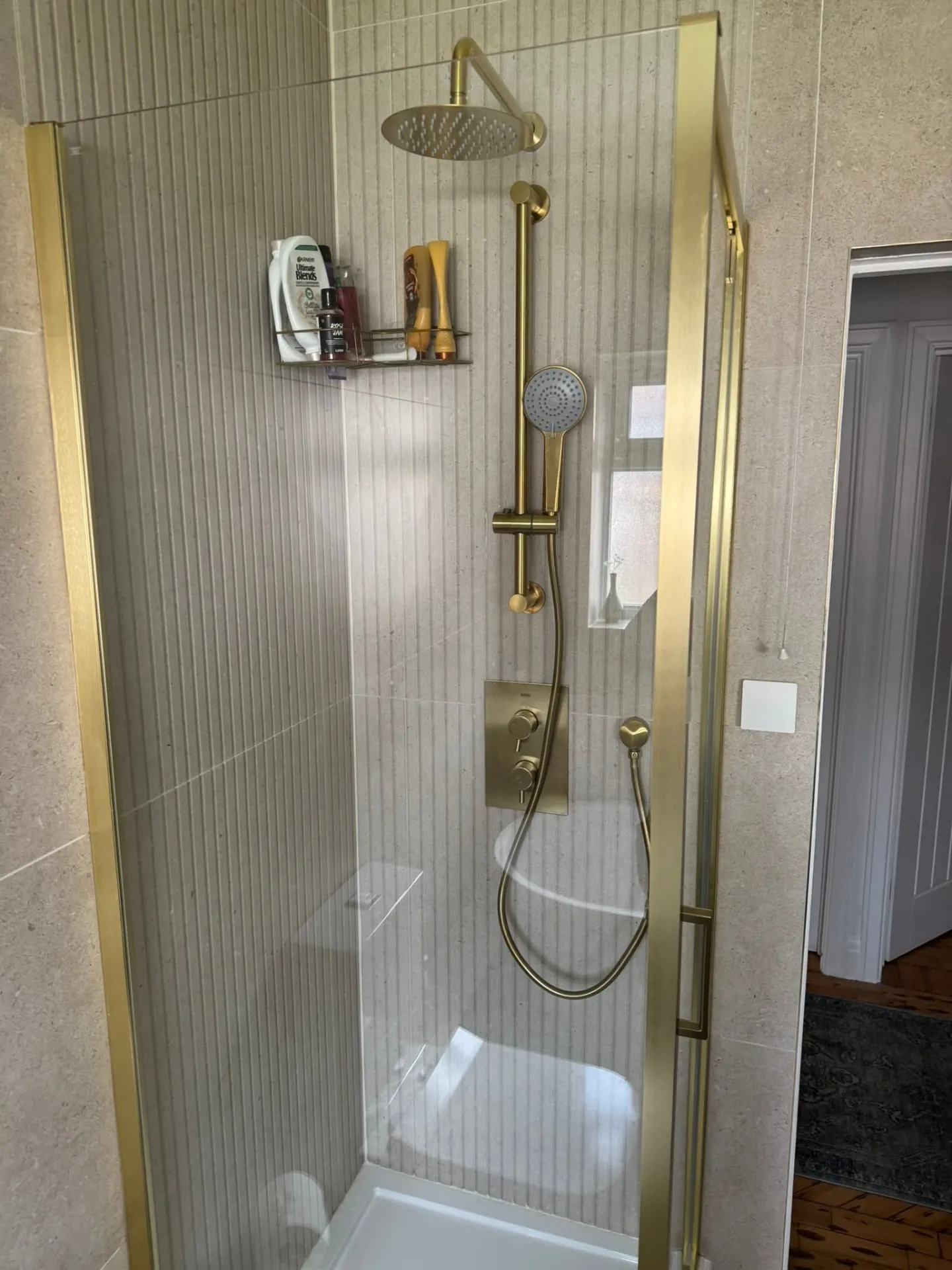 Bathroom installation by Space B Tiling: brass shower enclosure with fluted stone-effect tiles
