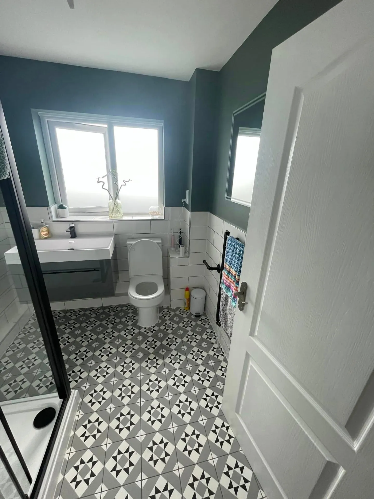 Bathroom installation by Space B Tiling: patterned floor tiles, toilet and basin under a green feature wall